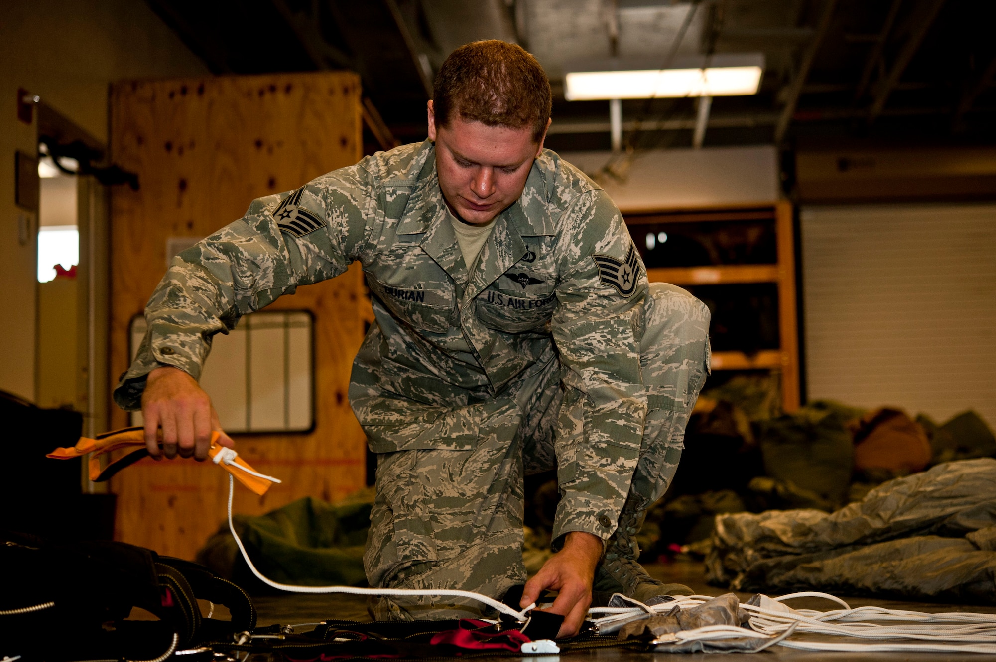 U.S. Air Force Staff Sgt. Kyle Burian, 58th Rescue Squadron aircrew flight equipment, repacks a MC5 parachute June 24, 2013, at Nellis Air Force Base, Nev. Aircrew flight equipment Airmen are responsible for inspecting, repacking, and rigging heavy equipment used to jump out of aircraft. (U.S. Air Force photo by Senior Airman Daniel Hughes)
