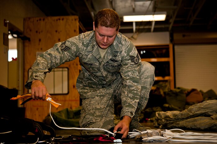 U.S. Air Force Staff Sgt. Kyle Burian, 58th Rescue Squadron aircrew flight equipment, repacks a MC5 parachute June 24, 2013, at Nellis Air Force Base, Nev. Aircrew flight equipment Airmen are responsible for inspecting, repacking, and rigging heavy equipment used to jump out of aircraft. (U.S. Air Force photo by Senior Airman Daniel Hughes)