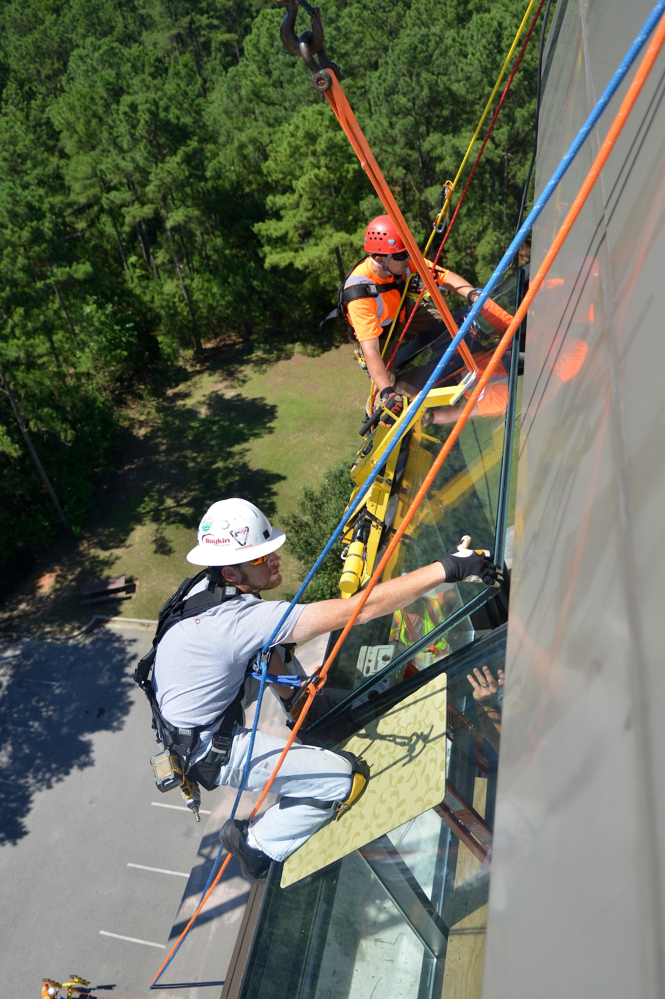 John Sorrentino and John Webster, Boykin contracting rope access glaziers hang from the ropes as they install new glass on the air tower, Shaw Air Force Base, S.C., June 21, 2013. The air tower has been undergoing maintenance since September,  which recently has lead into a replacement of all the windows. (U.S. Air Force photo by Airman 1st Class Ashley L. Gardner/Released)