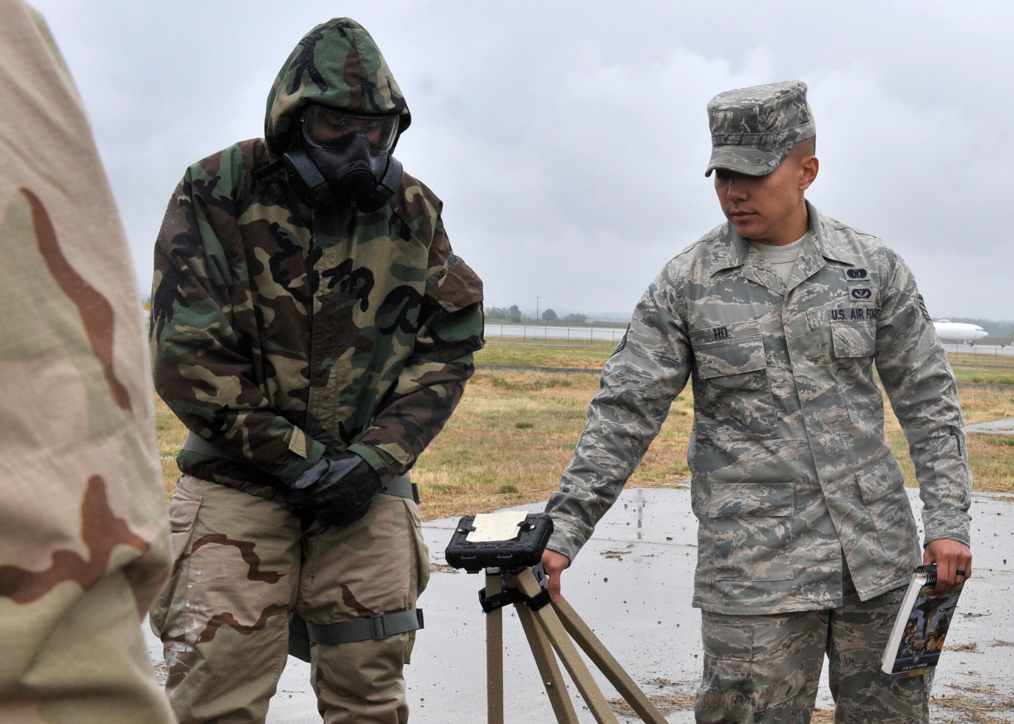 Staff Sgt. Casey Ho, 92nd Civil Engineer Squadron emergency management, shows members of Team Fairchild M-8 paper on a chemical stand and what to check for to determine if there is contamination during a post-attack reconnaissance sweep at Fairchild Air Force Base, Wash. June 20, 2013. Airmen were practicing the Ability to Survive and Operate training and 'mopped up' with mission oriented protective posture gear for a base exercise. (U.S. Air Force photo by Staff Sgt. Michael Means/Released)