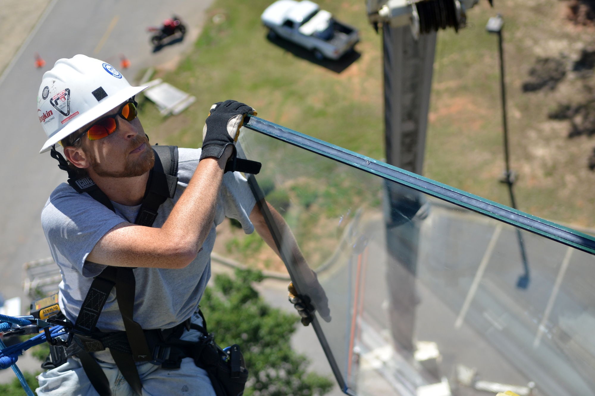 John Sorrentino, a Boykin contracting rope access glazier grips the new glass window while in the process of installation, Shaw Air Force Base, S.C., June 21, 2013. The air tower has been undergoing maintenance since September, which recently has led into a replacement of all the windows. (U.S. Air Force photo by Airman 1st Class Ashley L. Gardner/Released)