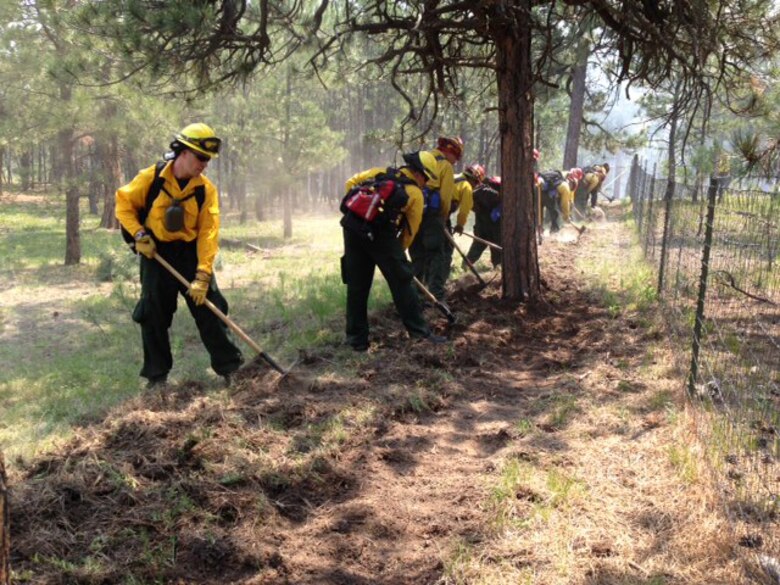 Two firefighters from the 721st Civil Engineer Squadron fire department work in concert with others to build a firebreak during the raging Black Forest Fire north of Colorado Springs. Firefighters and other emergency service personnel worked around the clock to extinguish the fire that began June 11. Operating under a mutual aid agreement, the CMAFS Fire Department was able to provide specially-trained firefighters within hours. (U.S. Air Force photo)