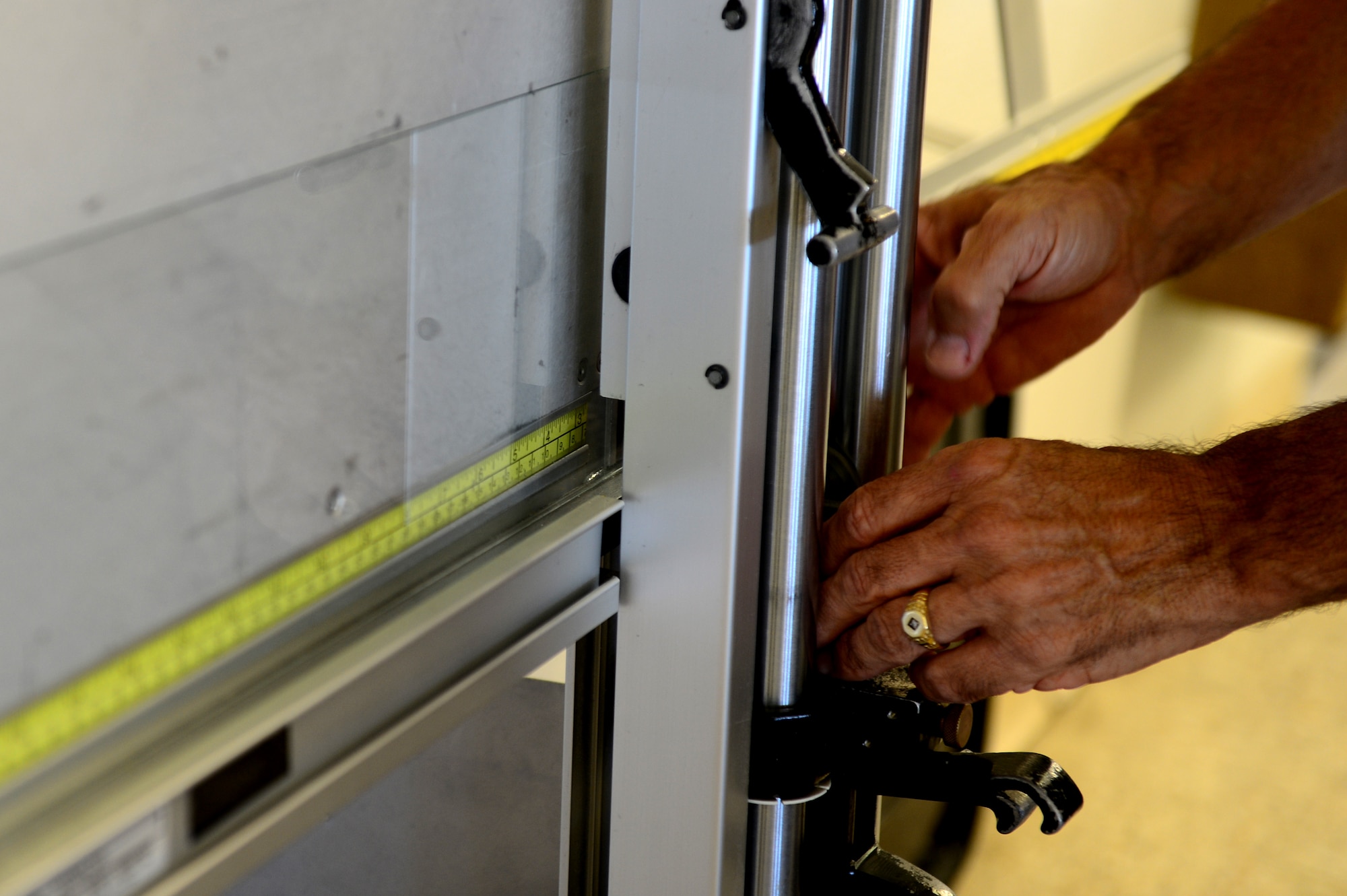 Ernie Sanchez, framing and matting instructor, demonstrates how to cut glass at Langley Air Force Base, Va., June 20, 2013. Sanchez teaches the framing and matting class, which equips the participants with the skills to build their own frames to showcase items. (U.S. Air Force photo by Senior Airman Kayla Newman/Released)