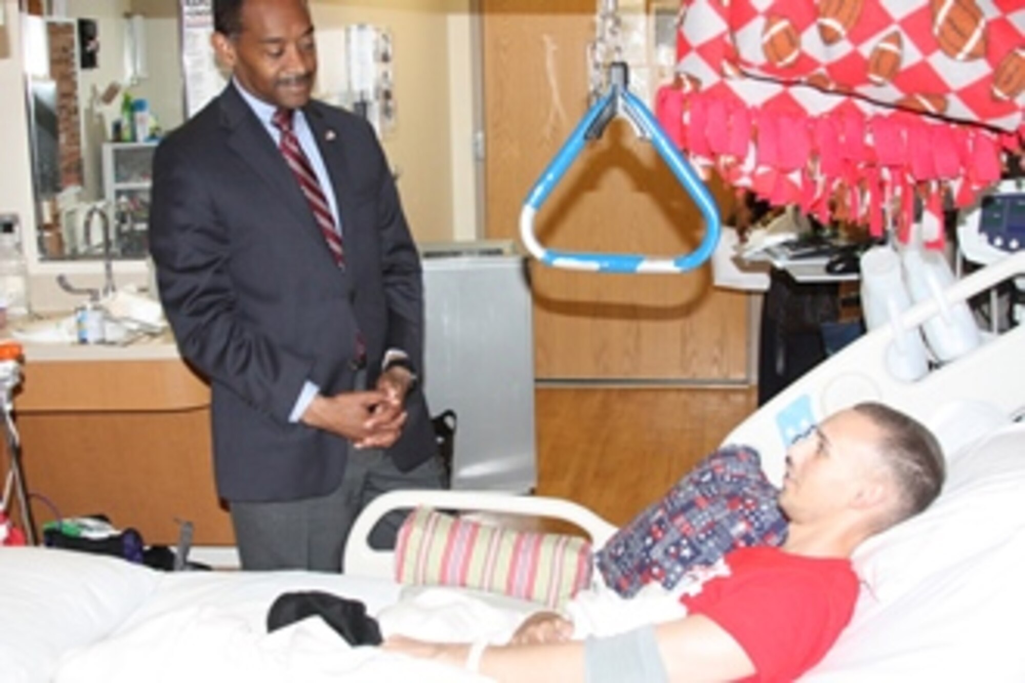 Dr. Jonathan Woodson, Assistant Secretary of Defense for Health Affairs and Director, TRICARE Management Activity, visits a wounded warrior,  Army Capt. Edward Klien, in his room at Walter Reed National Military Medical Center, June 7, 2013. (DoD photo by Bernard S. Little)