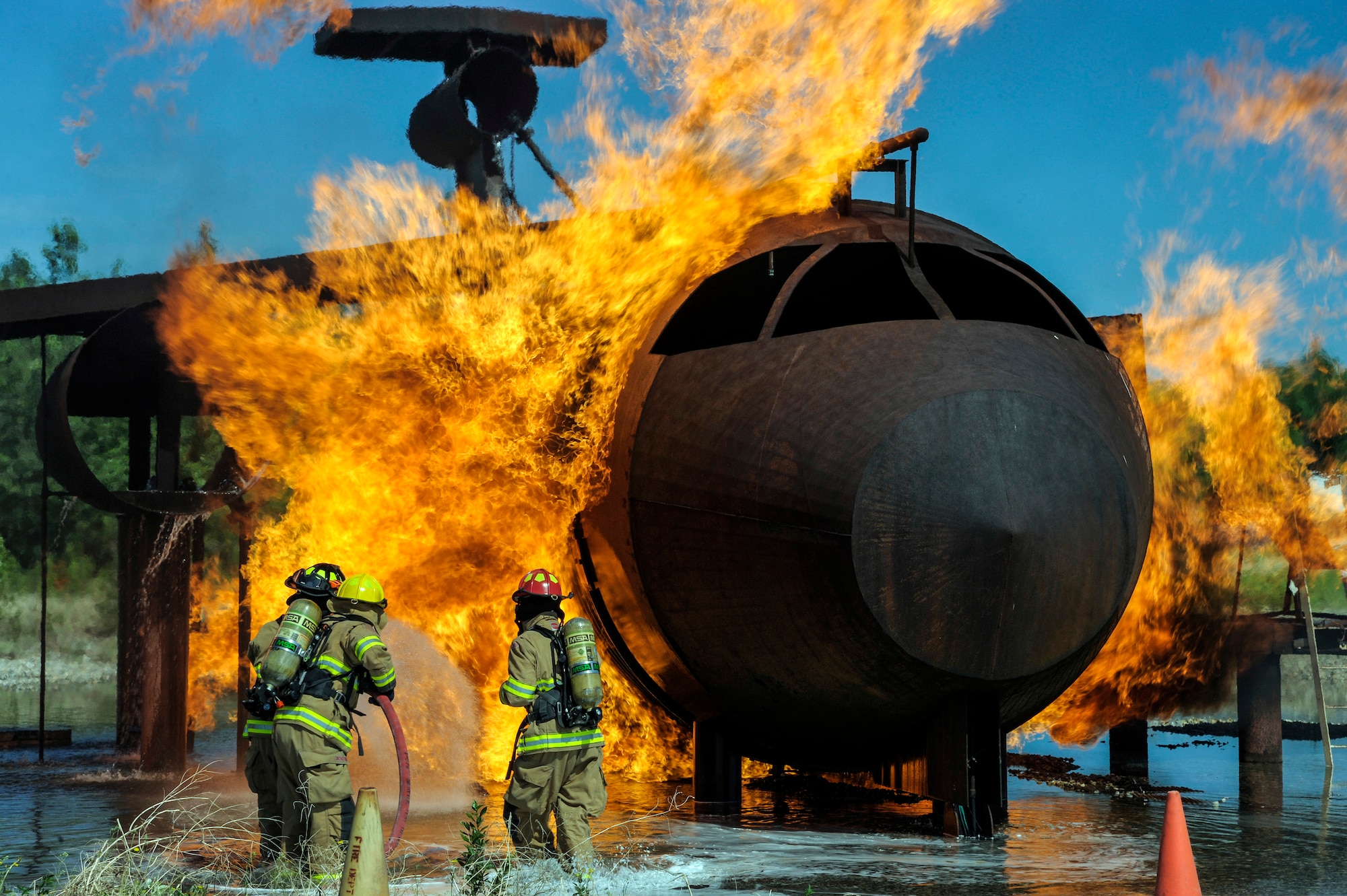 Firefighters with the 354th Civil Engineer Squadron Fire Department attempt to put out a flame on an aircraft fire trainer June 17, 2013, Eielson Air Force Base, Alaska. Fire training prepares firefighters to work as a team in the event that a fire hazard occurs. (U.S. Air Force photo by Senior Airman Zachary Perras/Released)