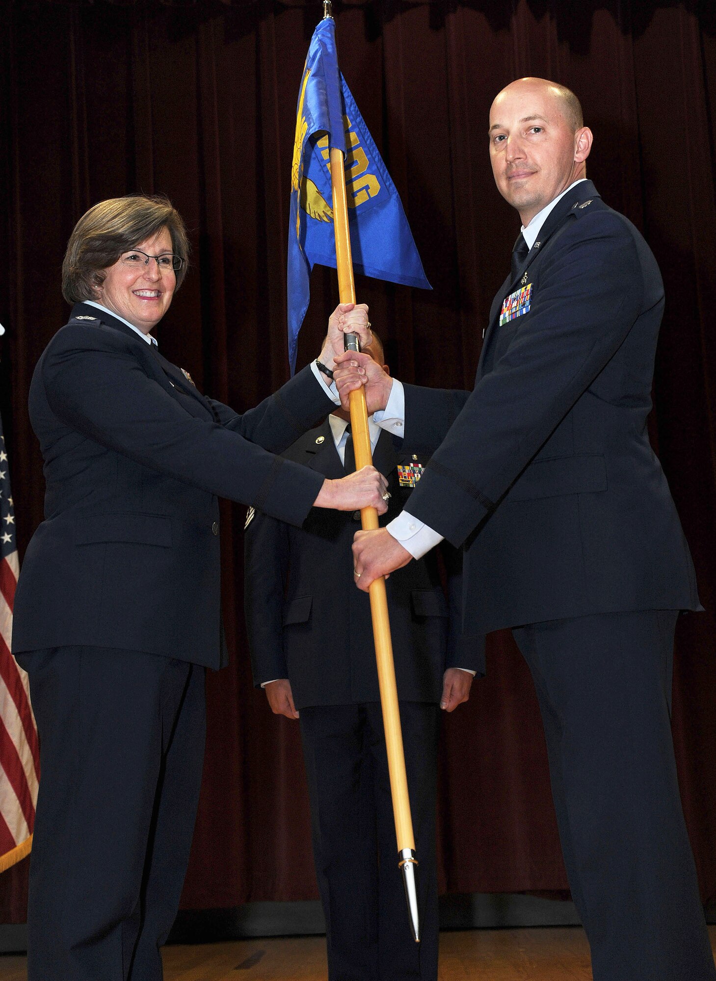 Col. Robin Schultze, 92nd Medical Group commander, hands the guidon to Lt. Col. Richard Broyer, 92nd Medical Support Squadron commander, during the 92nd MDSS change of command ceremony at Fairchild Air Force Base, Wash., June 24, 2013. The change of command is a tradition that represents a formal transfer of authority and responsibility. (U.S. Air Force photo by Airman 1st Class Janelle Patiño/Released)