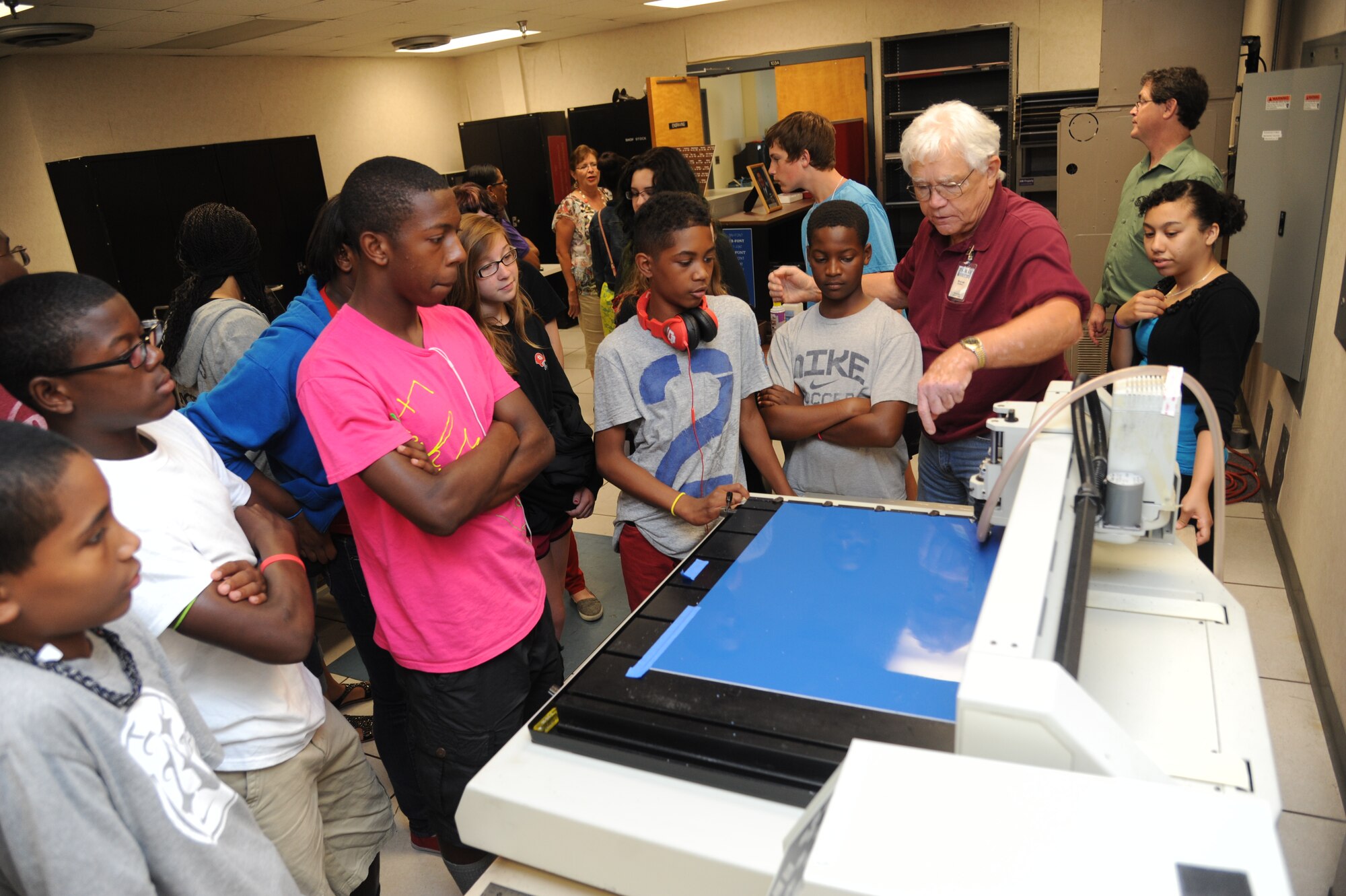 Terry Lee, K-Mar Industries contract illustrator, shows how an engraving machine works to children from the youth center June 21, 2013, at Wall Studio, Keesler Air Force Base, Miss.  The youth center teen summer camp program also toured the public affairs office and other visual information services such as photo, video, graphics.  (U.S. Air Force photo by Kemberly Groue)