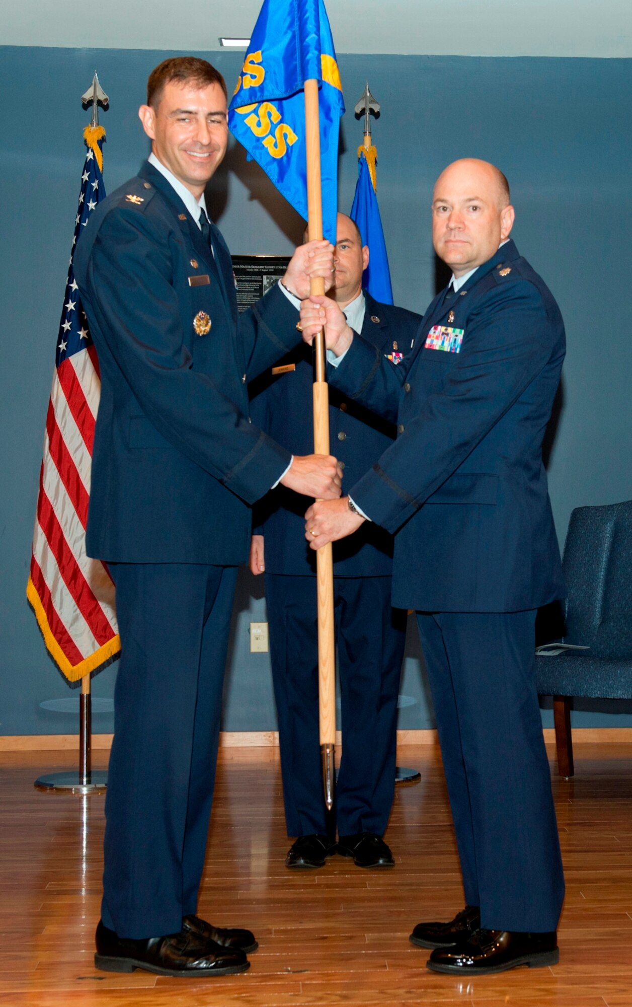 Col. Paul Skala, 325th Medical Group commander, passes the 325th Medical Support Squadron  guidon to Lt. Col. Rodney Jorstad, 325th MDSS commander,  during a change of command ceremony June 24 while Master Sgt. Scott Jenkins, 325th MDSS superintendent, looks on.