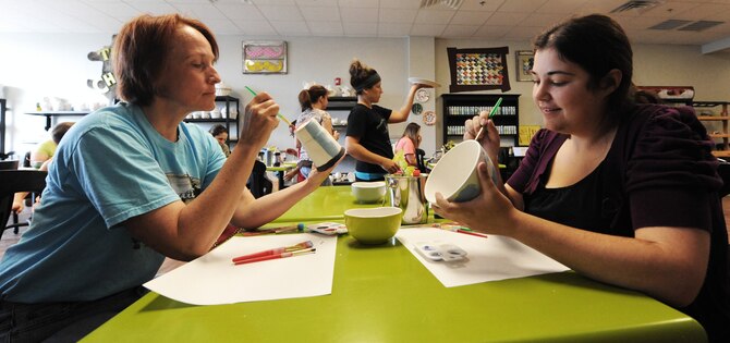 Senior Master Sgt. Mary-Dale Amison, 131st Bomb Wing Public Affairs superintendent, paints pottery with Lillian Johnson, 20th Reconnaissance Squadron sensor operator, during a Hearts Apart event at the Chartreuse Moose in Warrensburg, Mo., June 17, 2013. Although the event was targeted at spouses and dependents with deployed family members, anyone on base can attend. (U.S. Air Force photo by Staff Sgt. Nick Wilson/Released)