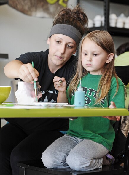 Cassie Krzys, wife of John Krzys, from the 509th Logistics Readiness Squadron, paints pottery with her daughter during a Hearts Apart event at the Chartreuse Moose in Warrensburg, Mo., June 17, 2013. Hearts Apart is a program the military uses to keep families connected while  Service members are deployed. (U.S. Air Force photo by Staff Sgt. Nick Wilson/Released)