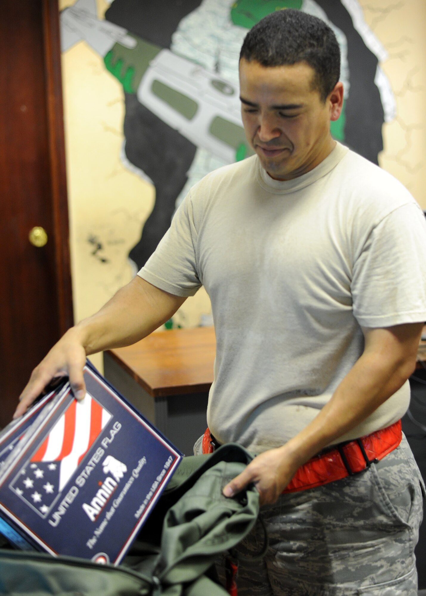Staff Sgt. Francisco Villa unpacks a bag of freshly flown flags to be paired with a certificate and distributed at the 379th Air Expeditionary Wing in Southwest Asia, June 21, 2013. Villa is a 34th Expeditionary Aircraft Maintenance Unit weapons load crew chief deployed from Ellsworth Air Force Base, S.D. (U.S. Air Force photo/Senior Airman Bahja J. Jones)
