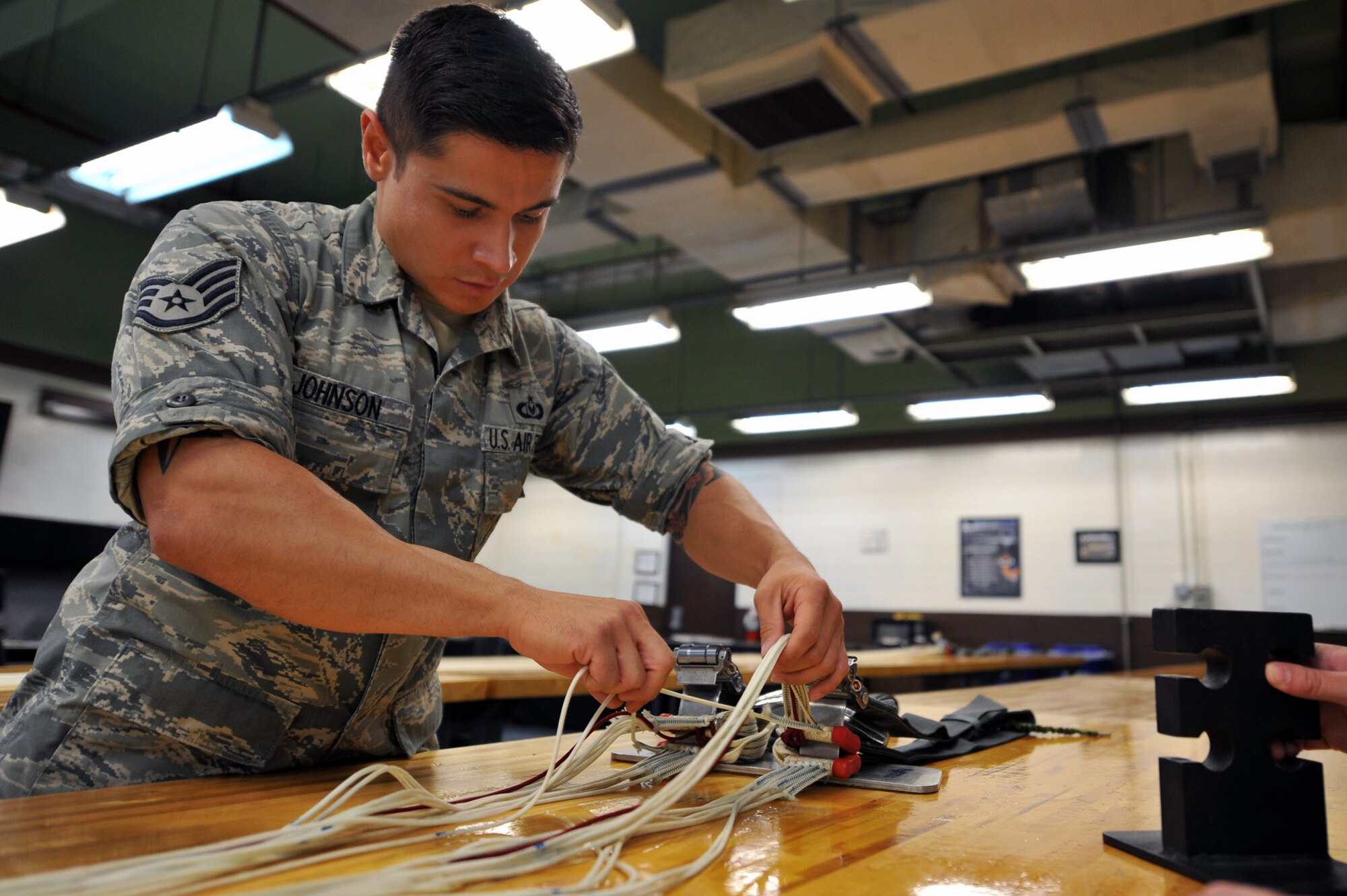 Staff Sgt. Ronald Johnson, 51st Operations Support Squadron aircrew flight equipment parachute section NCO in charge, checks suspension-line separation during a routine maintenance parachute packing at Osan Air Base, Republic of Korea, June 24, 2013. Johnson is responsible for checking the technician’s work by performing periodic inspections during the packing process. (U.S. Air Force photo/Senior Airman Alexis Siekert) 