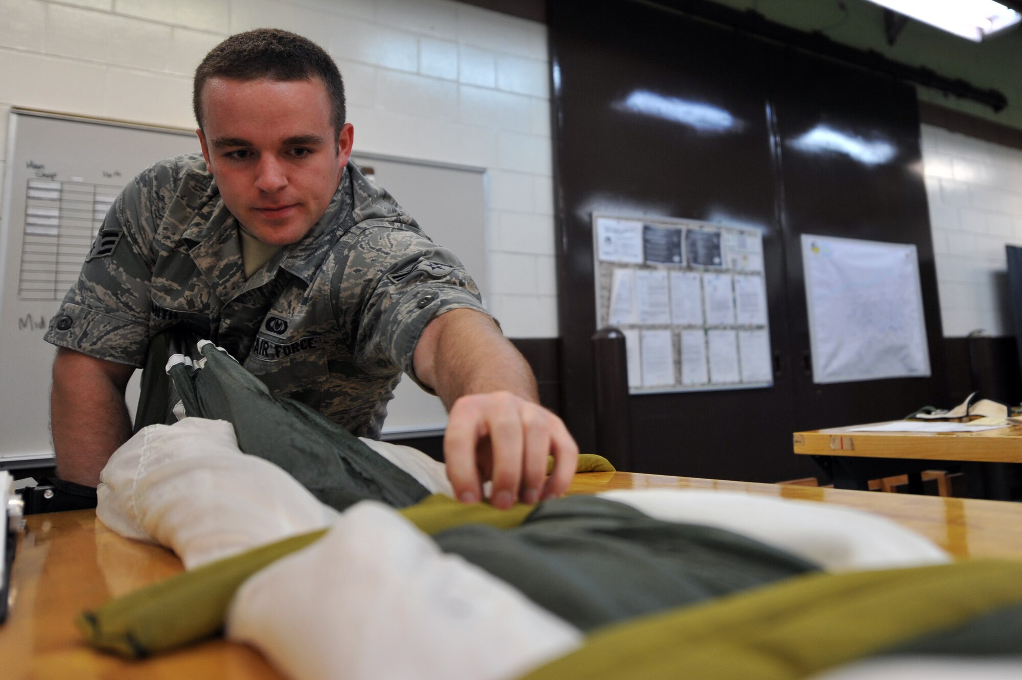 Senior Airman Taylor Smith, 51st Operations Support Squadron aircrew flight equipment journeyman, removes a weight from a folded canopy while packing it into its container at Osan Air Base, Republic of Korea, June 24, 2013. Technicians in the AFE section are responsible for the upkeep and handling of all parachutes on base. There are two different types of parachutes used here, Drogue and Advanced Concept Ejection Seat II recovery. (U.S. Air Force photo/Senior Airman Alexis Siekert)