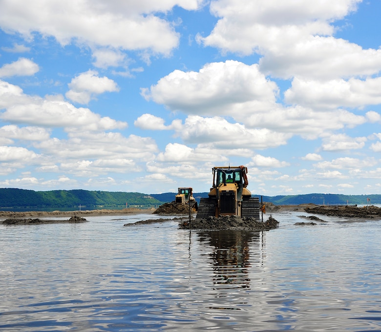 Walking on water? Not quite. One aspect of the Corps of Engineers not often seen is our Environmental Management Program. Here, a bulldozer moves dredge material to create islands in the Mississippi River. Specifically, the Capoli Slough Habitat Restoration project is located in Pool 9, downstream of Lansing, Iowa, on the Wisconsin side of the river, where erosion from wave action and main channel flows is reducing the size of wetland areas. This has resulted in the loss of aquatic vegetation and the shallow habitats important for the survival of many species of fish and wildlife. The project is broken down into two stages, and consists of creating 12 islands, improving backwater habitat, bank stabilization and other measures to improve the habitability. Once completed, the project will be turned over to the U.S. Fish and Wildlife service for day-to-day management.