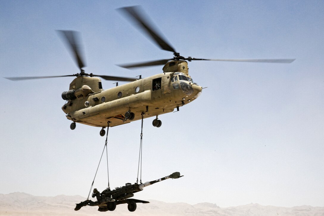 A M777A2 howitzer sling-loaded to a CH-47 Chinook helicopter is airlifted from Forward Operating Base Hadrian in Deh Rawud village in Uruzgan province to Kandahar Airfield in Afghanistan’s Kandahar province, June 18, 2013.