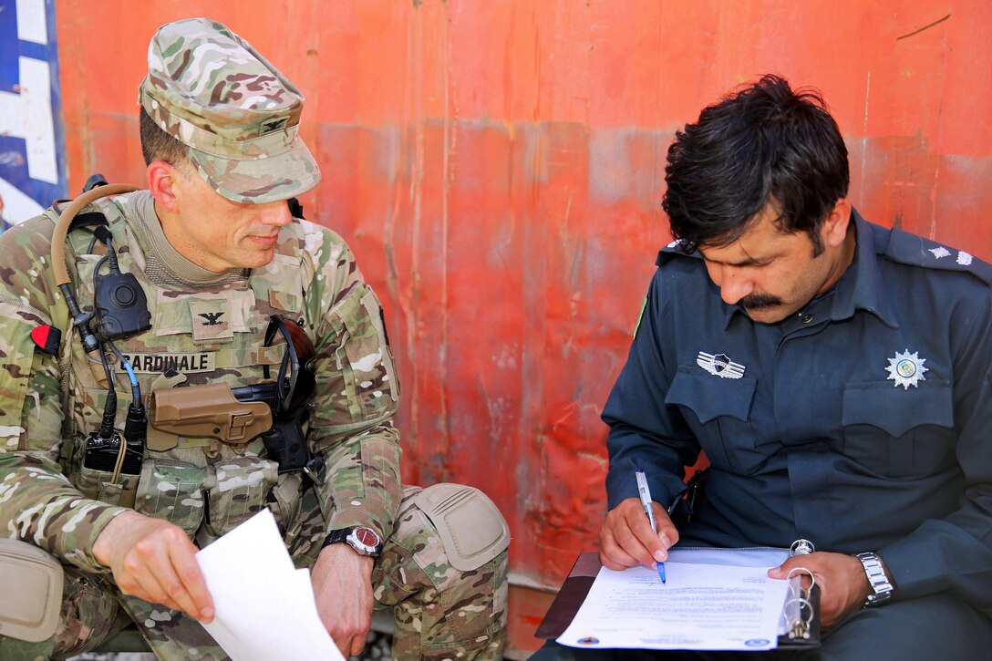 U.S. Army Col. Douglas C. Cardinale, left, and Haji Mematulla, right, deputy police chief of Deh Rawud village, sign documents handing over former Forward Operating Base Hadrian in Uruzgan province, Afghanistan, June 22, 2013. Cardinale is commander of the 3rd Infantry Division's 2nd Brigade Combat Team, and deputy commander of Combined Team Uruzgan.