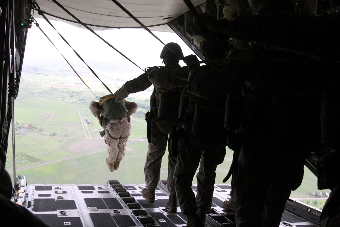A Marine serving with 1st Reconnaissance Battalion leads his peers in a static line jump here, June 22, 2013. The battalion performed jumps with 4th Recon Bn. to maintain their qualifications and sharpen their airborne skills. After performing static line jumps, many Marines completed one of the prerequisites to earn the Navy and Marine Corps Parachutist insignia. To earn the insignia, a Marine or sailor who has already completed the Basic Airborne course must complete a minimum of five static line jumps, including one combat equipment day jump, two combat equipment night jumps and exit from at least two different types of military aircraft.