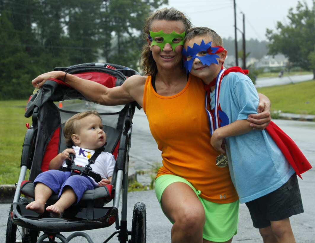 Christine Orndorff embraces her son after competing in Tarawa Terrace Community Center’s Superhero Fun Run with her children, June 22. Orndorff is dressed as Megamom, an original character. Ordnorff and her family were a few costumed heroes among the many who dressed the part for the event. While it is encouraged, participants are not required to dress up according to the Fun Run’s monthly theme.