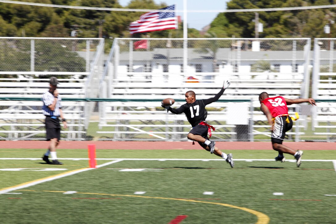 Sgt. Lorenzo Jarrett sprints toward the goal line, struggling to keep his footing, while Lance Cpl. Julian McCall lunges at Jarrett’s flag during the Championship game of the Commanding General’s Flag Football Tournament at the 11-Area football field here June 26. The double-elimination competition was made up of 34 10-man teams from units here. Jarrett is a warehouse clerk for Combat Logistics Regiment-15, 1st Marine Logistics Group here. McCall is a student at the Center for Naval Aviation Technical Training, Marine Corps Air Station here. For more information on the CG’s competition, visit www.mccscp.com/athletics.