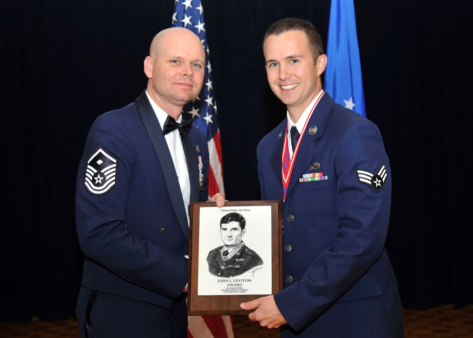 VANDENBERG AIR FORCE BASE, Calif. -- Master Sgt. Cecil Tonguet, 30th Security Forces Squadron first sergeant and guest speaker, presents Senior Airman Timothy Cram, 30th Comptroller Squadron lead defense travel administrator, with the distinguished John Levitow Award during an Airman Leadership School graduation ceremony here Thursday, 20 June. The John Levitow Award is the highest honor presented to a graduate of Air Force Enlisted Professional Military Education (PME), including Airman Leadership School, NCO Academy, and the Senior NCO Academy. (U.S. Air Force photo/Michael Peterson)