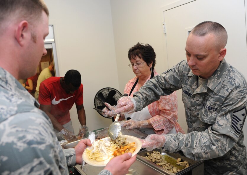 Master Sgt. Phillip Brandley, right, the 71st Mission Support Group first sergeant, and Jean Null, with the 71st Flying Training Wing Staff Judge Advocate’s office, serve food to Airmen during  the Singles’ International Gourmet Meal Opportunity June 24 in the Community Chapel Activity Center at Vance Air Force Base, Okla. This month’s theme was Italian food.  (U.S. Air Force photo/ Senior Airman Frank Casciotta)