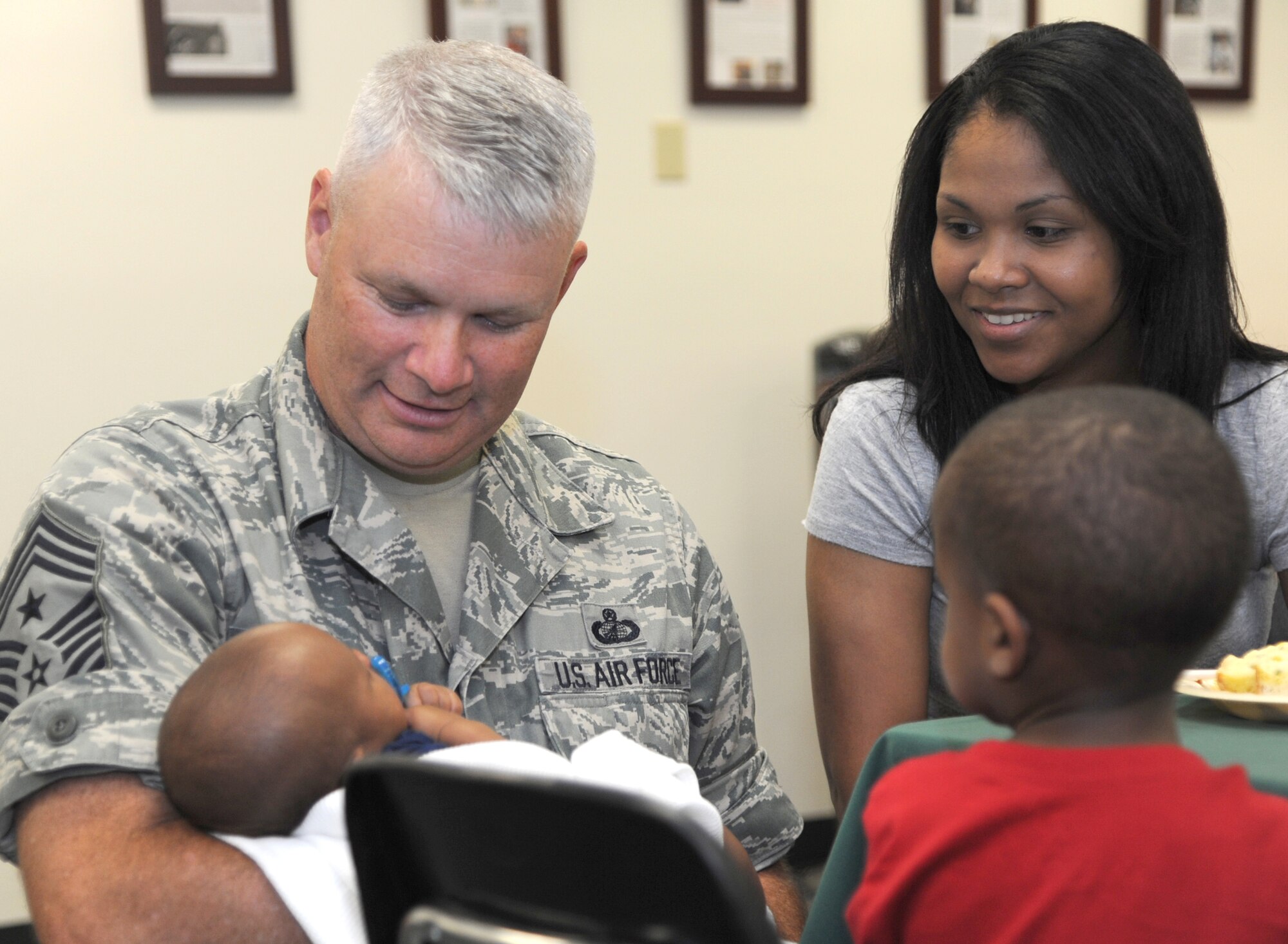 Chief Master Sgt. Mark Aman, left, the 71st Flying Training Wing command chief, sits with Staff Sgt. Erica McKissick, with the 71st FTW Staff Judge Advocate’s office, and her children June 24 in the Community Chapel Activity Center at Vance Air Force Base, Okla. SIGMO provides a free meal each month to all single Airmen – officer and enlisted – and families of deployed Airmen. (U.S. Air Force photo/ Senior Airman Frank Casciotta)