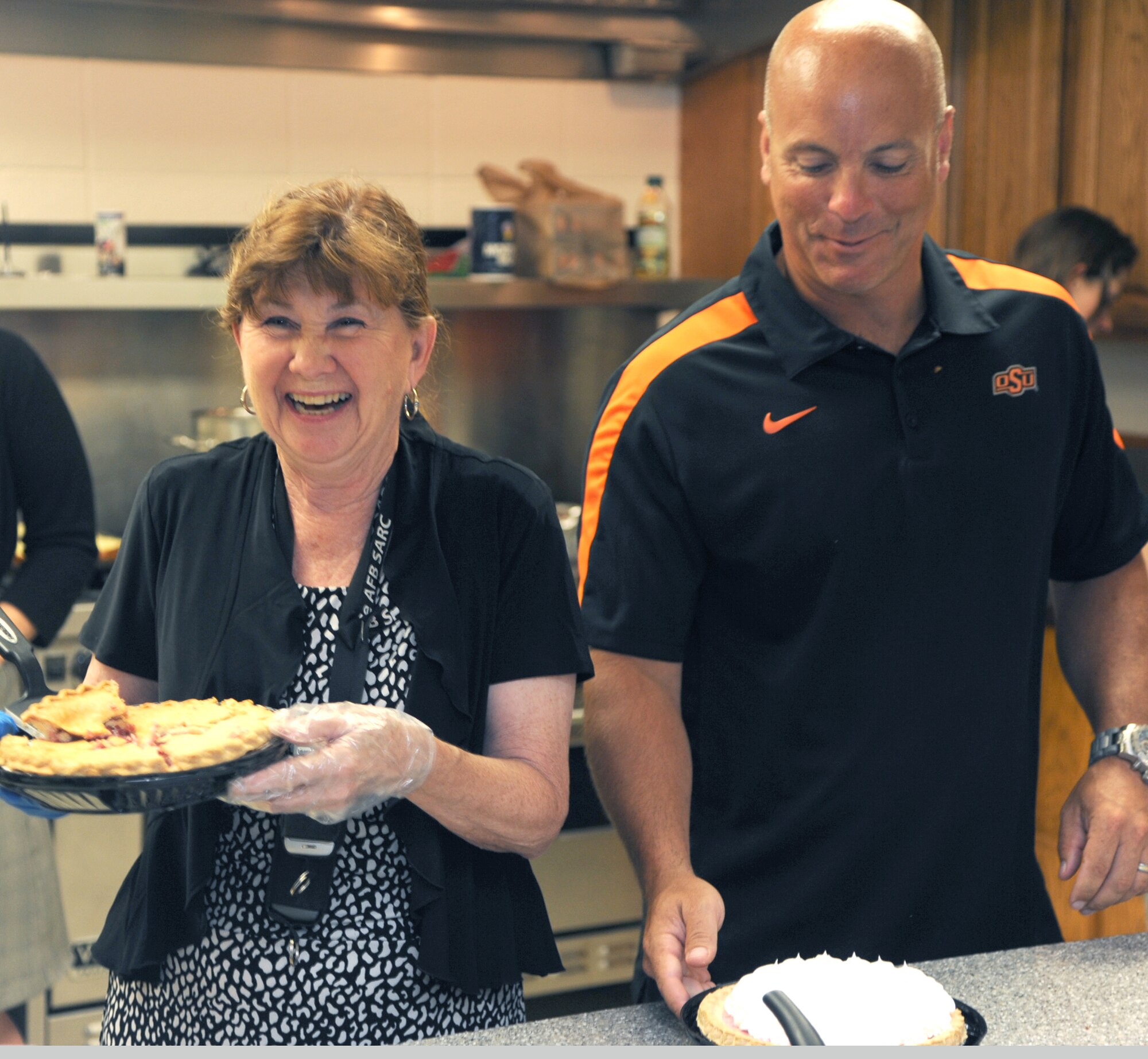 Terri Presa, left, the Sexual Assault Response Coordinator, and Lt. Col. Jason Pax, the 71st Flying Training Wing director of staff, prepare pies for the Singles’ International Gourmet Meal Opportunity June 24 in the Community Chapel Activity Center at Vance Air Force Base, Okla.  Thirty-seven volunteers served diner to more than 250 Airmen. (U.S. Air Force photo/ Senior Airman Frank Casciotta)