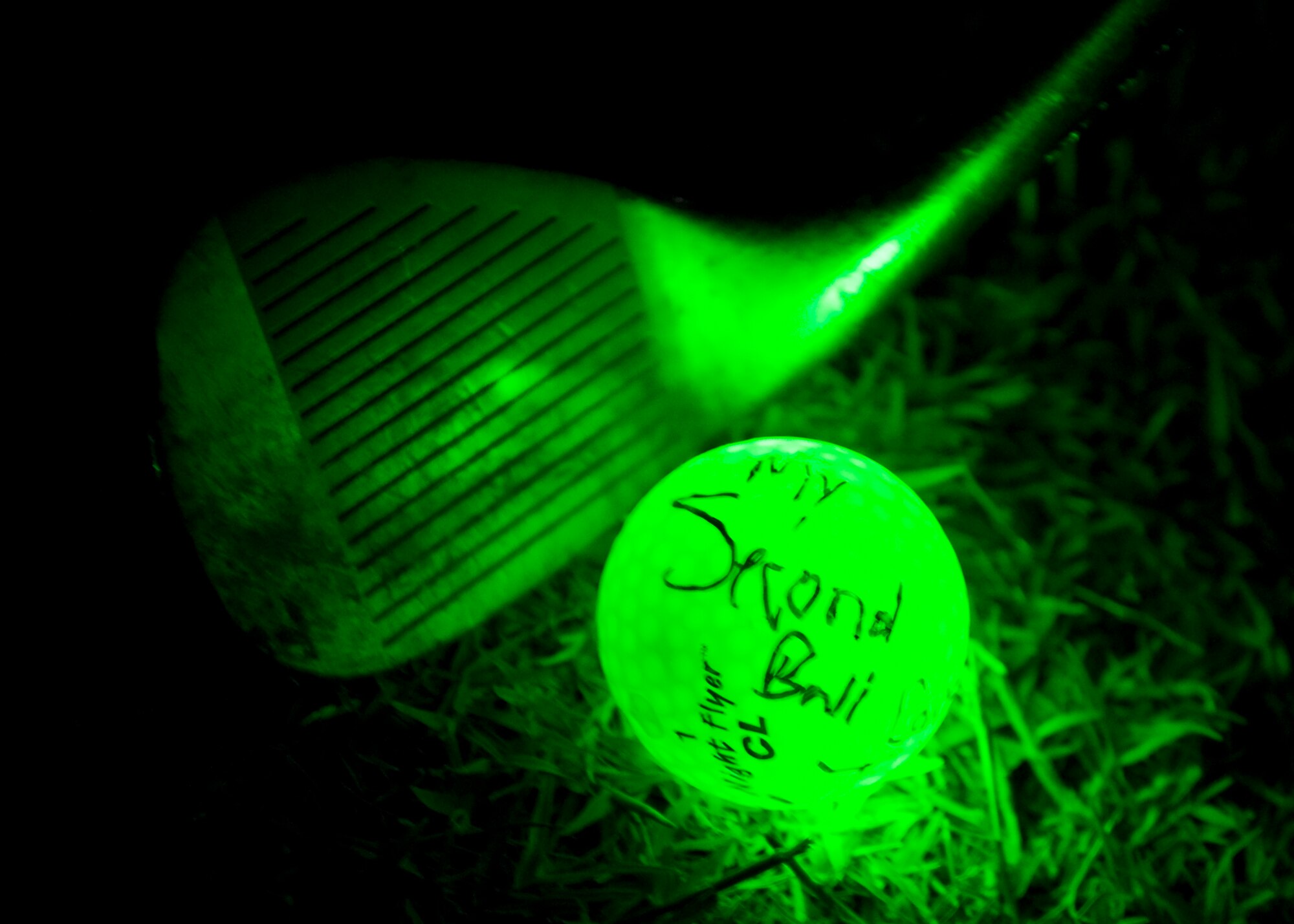 A golf club is positioned to hit a glow-in-the-dark golf ball June 21, 2013, at Dyess Air Force Base, Texas. Hosted by the 7th Security Forces Squadron, the night golf tournament raised more than $1,000 for the Defender’s Association and the Taylor County Sherriff’s Office. (U.S. Air Force photo by Airman Autumn Velez/Released)