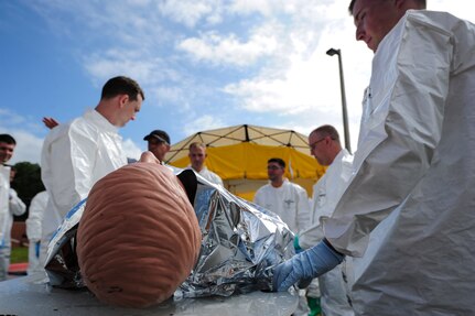 Sailors from the Navy Health Clinic Charleston simulate wrapping a patient with a Mylar blanket during the First Receivers Operations Training course June 21, 2013, at Joint Base Charleston - Weapons Station, S.C. The Mylar blanket would be used by the NHCC team to reduce heat loss in a person's body caused by thermal radiation, water evaporation and convection. The NHCC team participated in the FROT course to educate their Sailors on life-saving skills consisting of triage, initiate field treatment, decontaminate and save victims from Chemical, Biological, Radiological/Nuclear, or Hazardous Material. The 16-hour course consisted of one, eight-hour day of class lecture and a second eight-hour day of "hands-on" teamwork training to include a final "timed" exercise. (U.S. Air Force photo/Staff Sgt. Rasheen Douglas)