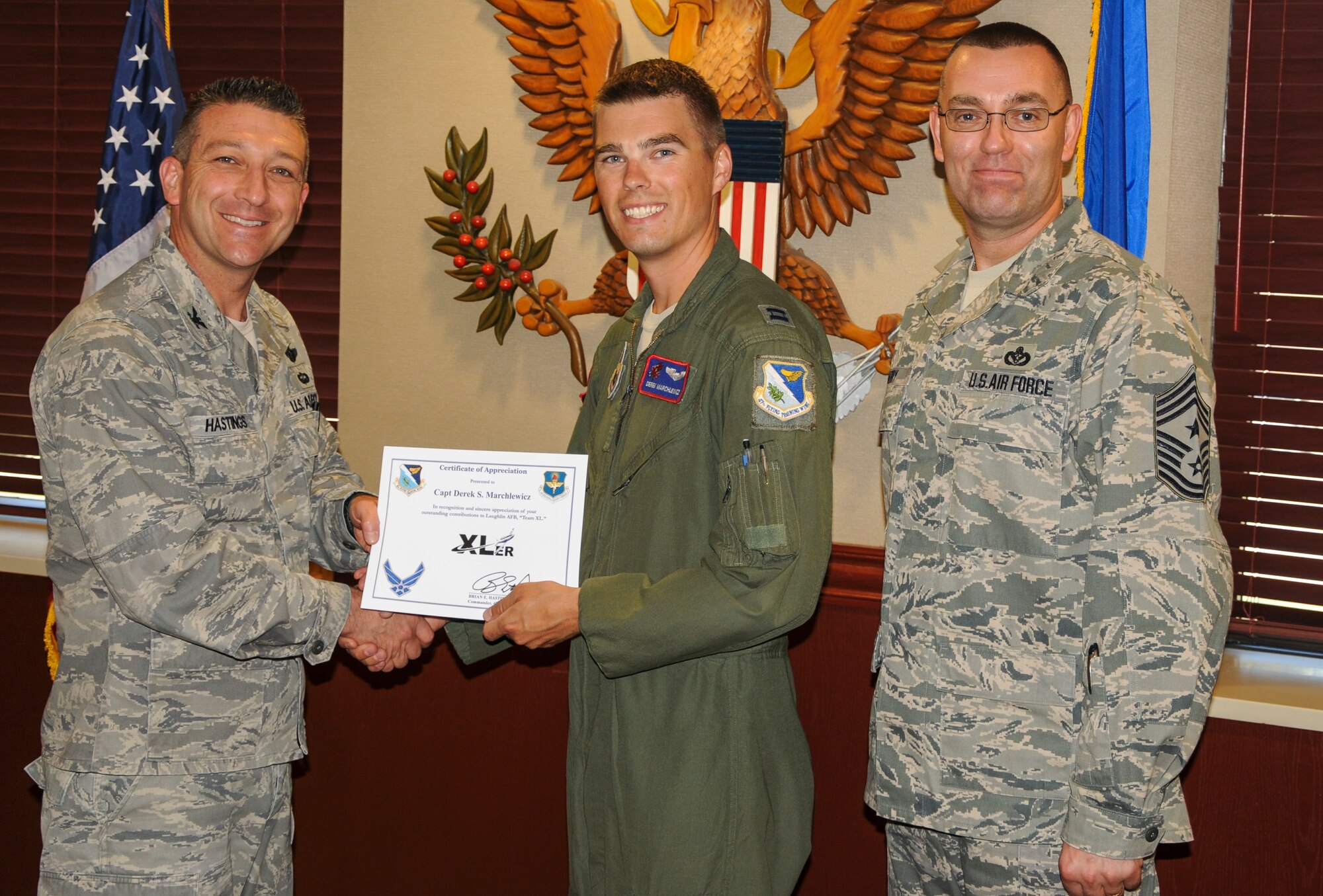 Capt. Derek Marchlewicz, 434th Flying Training Squadron assistant operations officer, poses with Col. Brian Hastings, 47th Flying Training Wing commander, and Chief Master Sgt. Garry Berry, 47th FTW command chief, after being presented the XLer of the week award here June 4, 2013. The XLer is a weekly award chosen by wing leadership and given to those who consistently make outstanding contributions to Laughlin and their unit. (U.S. Air Force photo/Joel Langton)