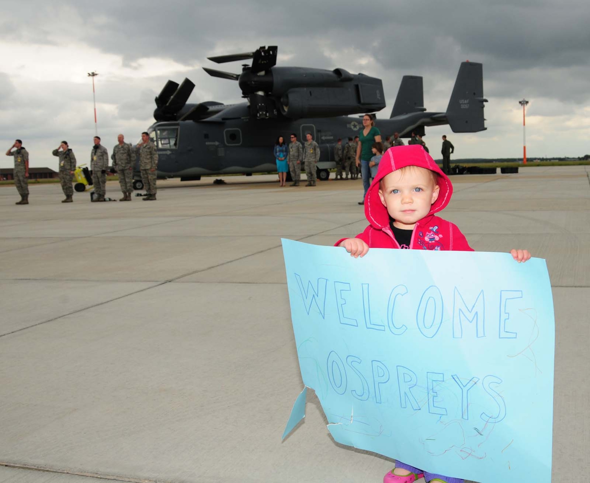 Elizabeth Hamilton, 19 months, daughter of Mary and Capt. Mark Hamilton, 7th Special Operations Squadron, is ready to greet her dad as he and other 7th SOS members arrive with two CV-22B Ospreys June 24, 2013, on RAF Mildenhall, England. Team Mildenhall members gathered to watch the CV-22 arrival and welcomed the crew and the aircraft to the base. (U.S. Air Force photo by Karen Abeyasekere/Released) 