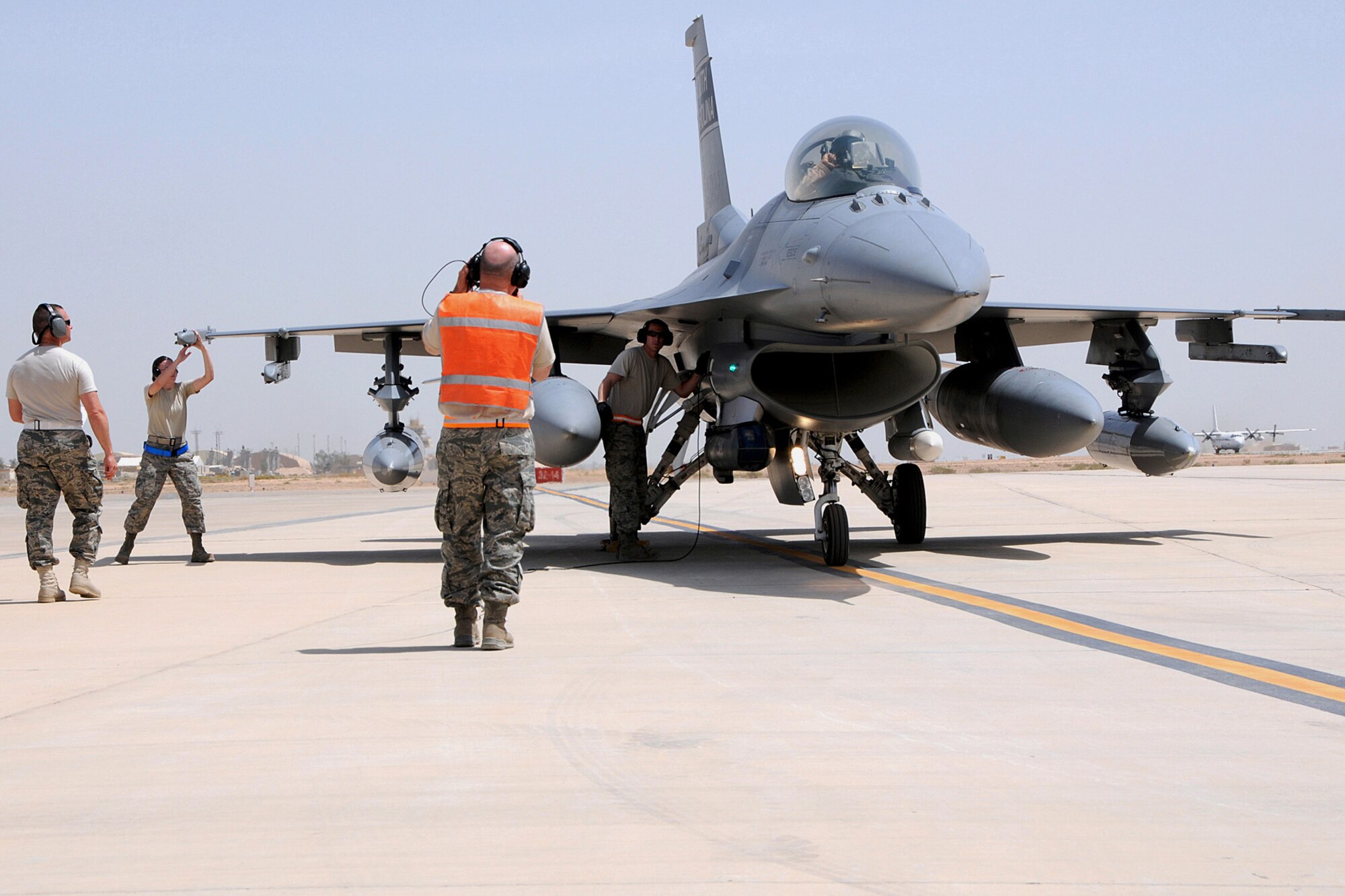 U.S. Air Force Tech. Sgt. Michael Bilberry, a crew chief with the 169th Aircraft Maintenance Squadron at McEntire Joint National Guard Base, South Carolina Air National Guard, marshals an F-16 Fighting Falcon from the 157th Fighter Squadron, that landed at Joint Base Balad (JBB), Iraq, May 16, 2010.  Staff Sgt. Kenneth Monroe (left), Airman 1st Class Lyla Rayer and Staff Sgt. Leonard Gajewsky (center) with the 169th Aircraft Maintenance Squadron, work to quickly de-arm the aircraft.  Personnel from McEntire are deployed to JBB on an Air Expeditionary Force rotation to take over the Air Tasking Order for the 332nd Air Expeditionary Wing.
(U.S. Air National Guard photo by Tech. Sgt. Caycee Watson/Released)
