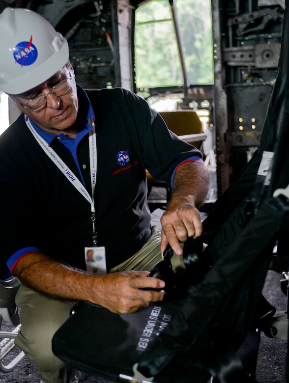 Richard Boitnott, NASA Langley Research Center senior aerospace engineer, inspects the seats inside a helicopter in preparation for a crash test set to take place later this year at the National Aeronautics and Space Administration Langley Research Center Landing and Impact Research Facility in Hampton, Va., June 18, 2013. The facility is considered a national resource for conducting crash tests for airplanes, helicopters and other manned vehicles, as researchers can control the exact conditions of a crash as well as gather of post-test information that contributes to safety worldwide.(U.S. Air Force photo by Airman 1st Class R. Alex Durbin/Released) (Badge blurred for security purposes) 