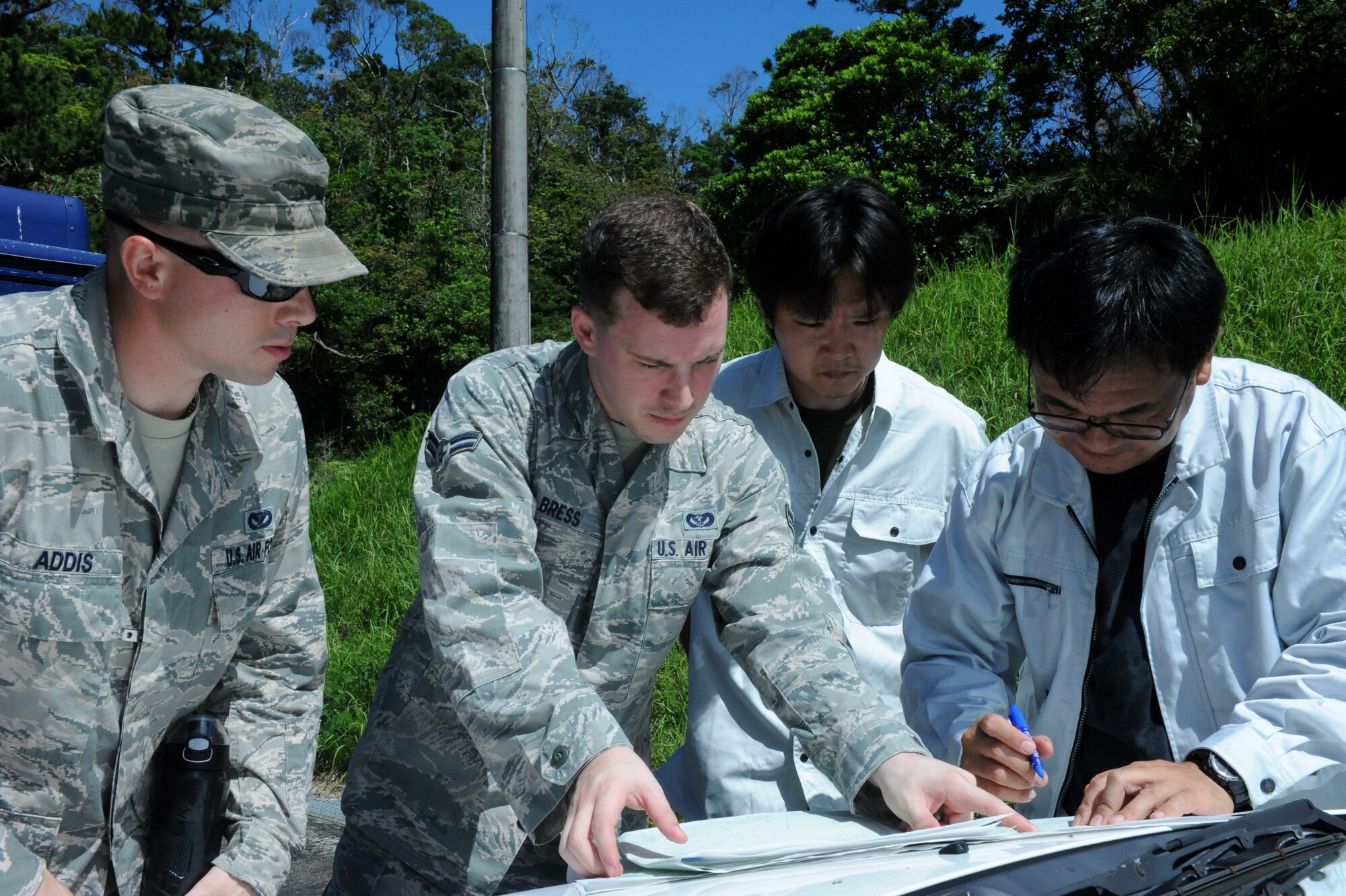 U.S. Air Force Senior Airman Scott Addis and Airman 1st Class Zachary Bress, 18th Civil Engineering Squadron pest management specialists, help Koki Terada, Okinawa Prefectural Government Institute of Health and Environment lab researcher, mark locations of snake traps on a map on Kadena Air Base, Japan, June 25, 2013. Terada placed approximately 49 snake traps throughout the 18th Munitions Squadron storage area to catch habu snakes. (U.S. Air Force photo by Airman 1st Class Hailey R. Davis/Released)