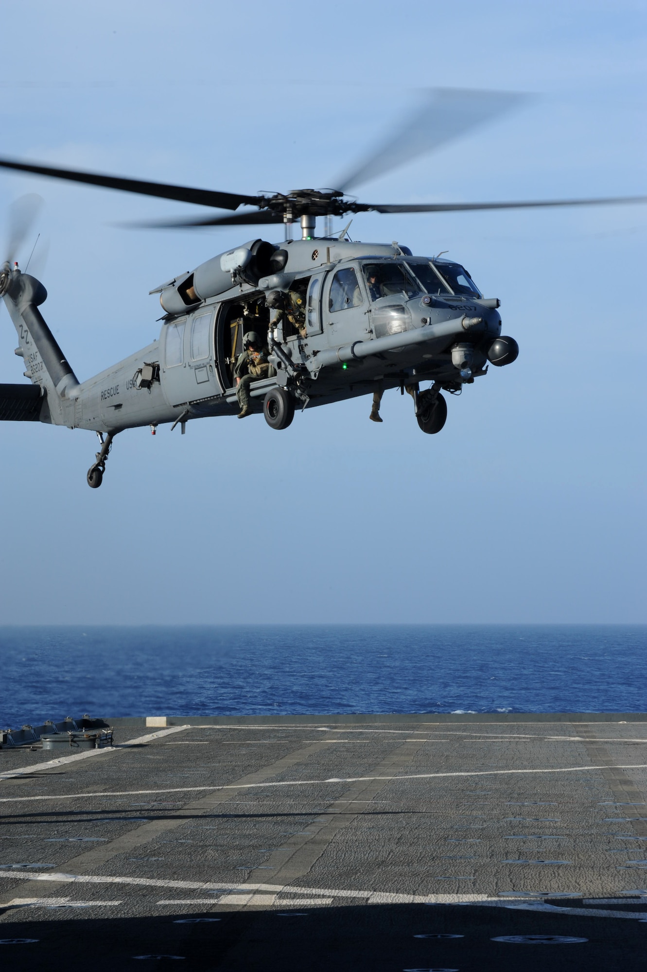 An HH-60G Pave Hawk helicopter prepares to land onto the deck of a naval ship off the coast of Okinawa, Japan, June 22, 2013. The primary mission of the helicopter and its crew is to conduct day or night recovery operations for medical evacuation, disaster response, humanitarian assistance, security cooperation and aviation advisory, and rescue command and control. (U.S. Air Force photo by Airman 1st Class Hailey R. Davis/Released)