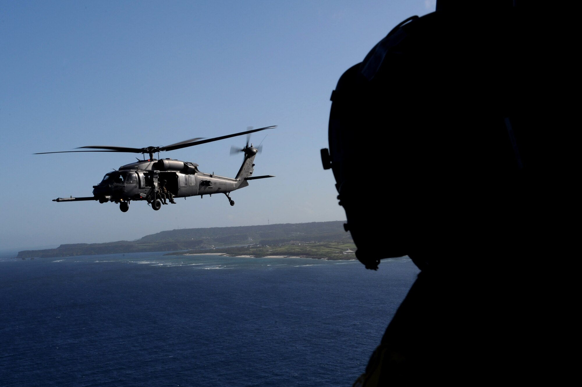A 33rd Rescue Squadron HH-60G Pave Hawk helicopter pilot watches an HH-60G Pave Hawk during a training mission off the coast of Okinawa, Japan, June 22, 2013. The primary mission of the helicopter and its crew is to conduct day or night recovery operations for medical evacuation, disaster response, humanitarian assistance, security cooperation and aviation advisory, and rescue command and control. (U.S. Air Force photo by Airman 1st Class Hailey R. Davis/Released)