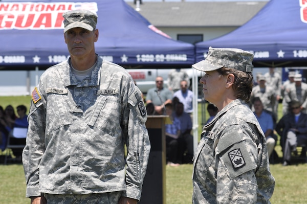 Lt. Col. J. Kaye Steed, the incoming commander of the 168th Military Police Battaion(right),and also a U.S. Army Corps of Engineers Nashville District Civil Engineering Technician stands ready to take the battalion colors from Col. Brett London, commander of the 194th Engineer Brigade during a change of command ceremony on June 14, 2013 at the Tennessee National Guard Volunteer Training Site-Milan in Lavinia, Tenn. Steed relieved Lt. Col. Barry L. Collins as the Commander of the 168th Military Police Battalion. 