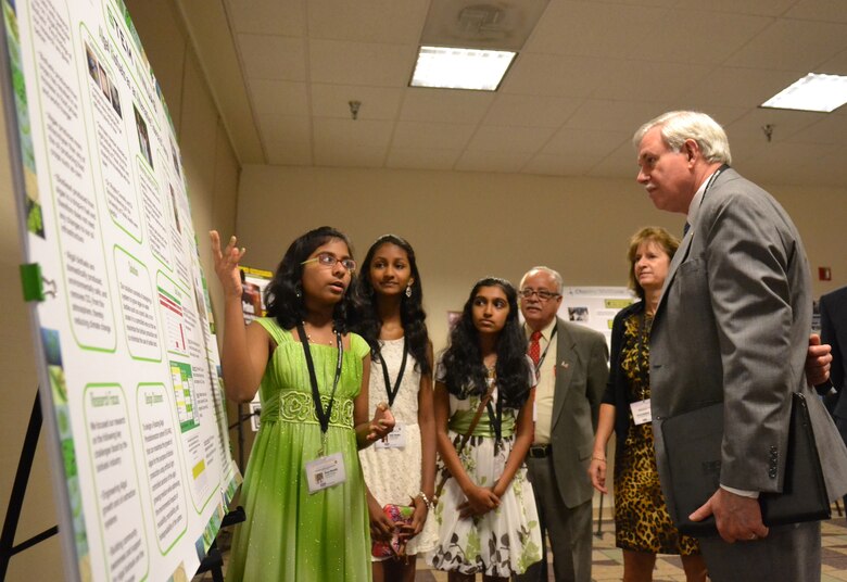Seventh-grader Divya Mereddy explains the project of her team, "STEM Ninjas," to Lloyd Caldwell, director of military programs for the U.S. Army Corps of Engineers, with teammates Rachana Subbanna and Sneha Thandra. The Corps' director of human resources, Sue Engelhardt, and Fidel Rodriguez look on. The STEM Ninjas won first place on June 21, 2013, for their grade in the 11th Annual eCYBERMISSION National Judging and Education Event. 