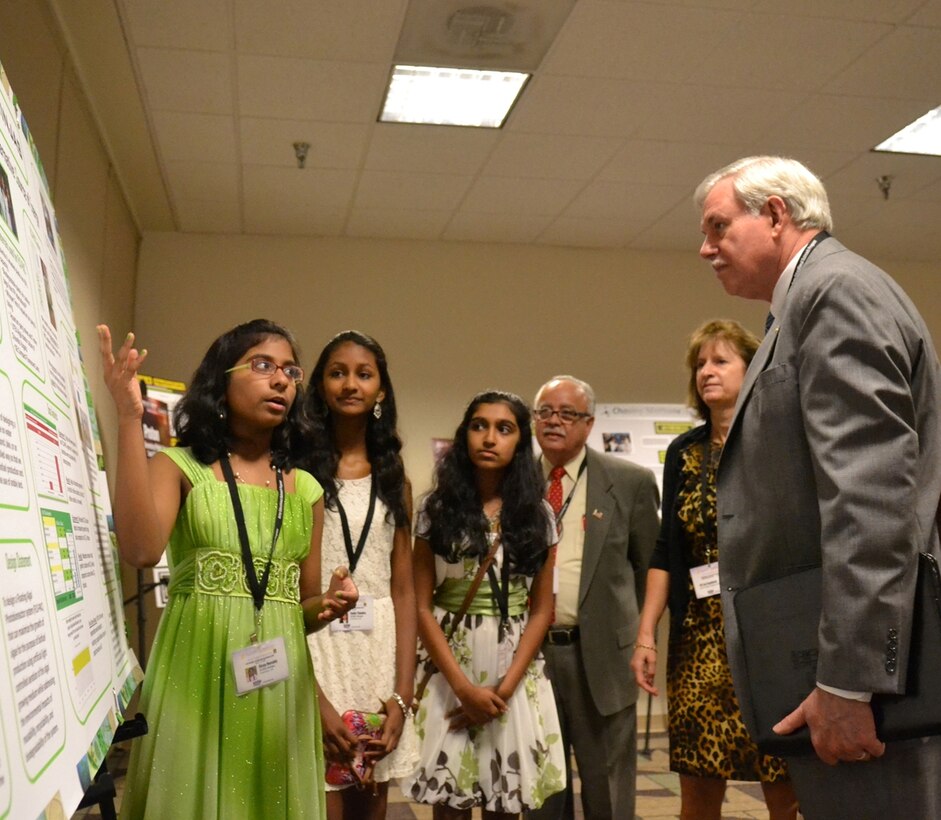 Seventh-grader Divya Mereddy explains the project of her team, "STEM Ninjas," to Lloyd Caldwell, director of military programs for the U.S. Army Corps of Engineers, with teammates Rachana Subbanna and Sneha Thandra. The Corps' director of human resources, Sue Engelhardt, and Fidel Rodriguez look on. The STEM Ninjas won first place on June 21, 2013, for their grade in the 11th Annual eCYBERMISSION National Judging and Education Event. 