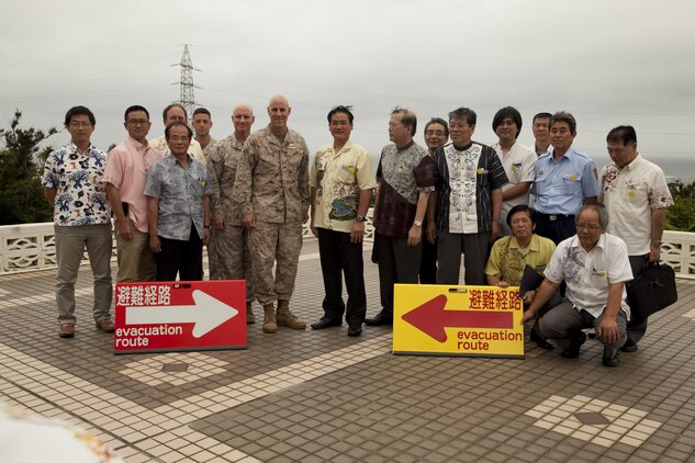 Ginowan City and Marine Corps Air Station Futenma officials pose for a photo next to evacuation route signs June 26 on MCAS Futenma. The leaders met to sign a bilateral agreement specifying procedures for evacuating Okinawa residents through the air station in the event of a natural disaster. The procedures also set the groundwork for future evacuation drills aboard the air station. (U.S. Marine Corps photo by Lance Cpl. Elizabeth A. Case/Released)