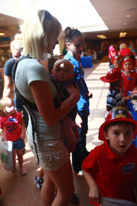 A military spouse visits one of the booths with her child to learn how to promote a healthy childhood during the Health and Fitness Fair at the station theater Friday.