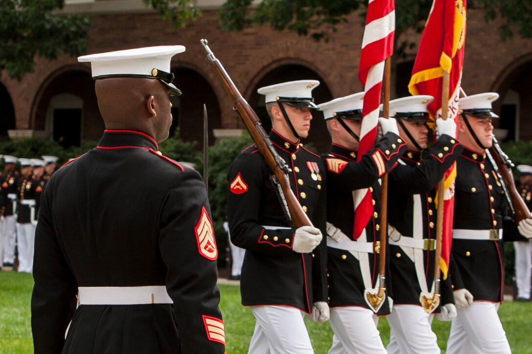The Marine Corps Color Guard marches by Staff. Sgt. Prince Covington, the ceremony adjutant, during a relief and appointment ceremony at Marine Barracks Washington, D.C., June 27. Sgt. Maj. Angela M. Maness, the Barracks sergeant major, assumed her post after relieving Sgt. Maj. Eric J. Stockton, former Barracks sergeant major. Stockton retired during the ceremony after more than 30 years of service.