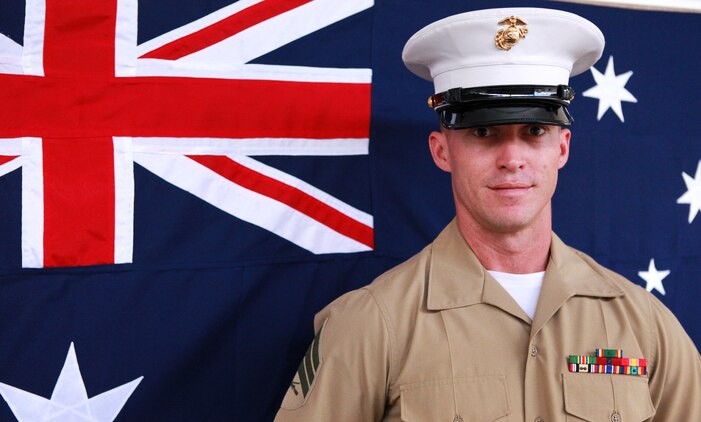 Sgt. Ian Polhamus, squad leader, 3rd Platoon, Lima Company, 3rd Battalion, 3rd Marine Regiment, Marine Rotational Force - Darwin, poses in front of an Australian flag, here, June 27. Polhamus lived Down Under for seven years. He said Australia feels like his home away from home.