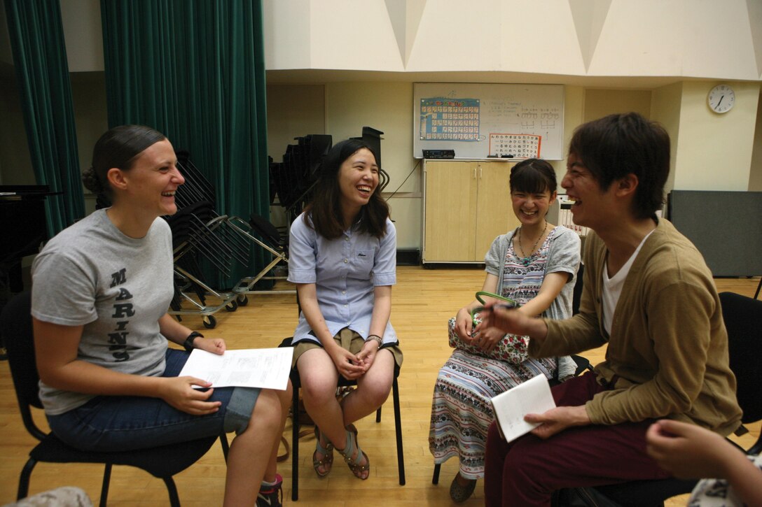 Lance Cpl. Amanda V. Davis, left, laughs with Japanese students June 19 at the III Marine Expeditionary Force Band Hall during a language and cultural exchange. The Marines and students traded cultural pointers and language skills. The students are with the University of the Ryukyus Wind Orchestra Band Club, and the Marines are with the III MEF Band. Photo by Lance Cpl. John S. Gargano