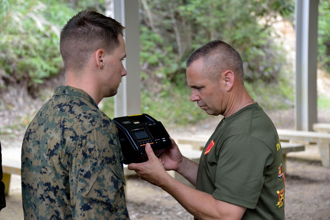 Mark Richter, right, measures the surface temperature of a prototype uniform material worn by Lance Cpl. Michael J. Cary June 19 at the Jungle Warfare Training Center. Cary and 32 other Marines’ core temperature, heart rate, skin temperature and respiration rate were continuously monitored through a physiological status monitor, to assess the performance of four prototype uniform materials. Richter is the program manager of the Marine Expeditionary Rifle Squad, Marine Corps Systems Command. Cary is a field artillery radio operator with 12th Marine Regiment, 3rd Marine Division, III Marine Expeditionary Force. (U.S. Marine Corps photo by Cpl. Mark W. Stroud/Released)