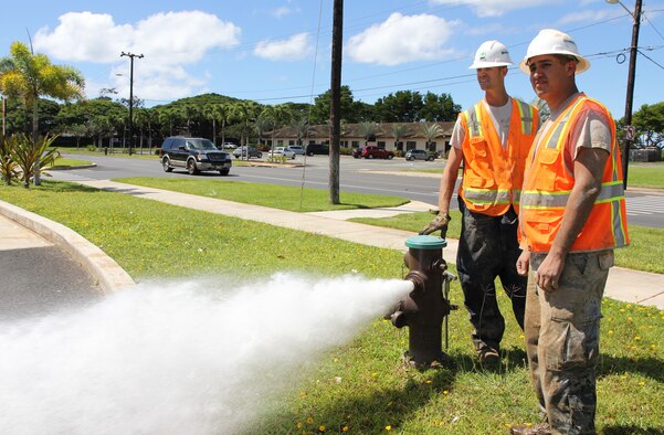 Tech. Sgt. Benjamin M. Johnson, left, job foreman and plumber with the 647th Civil Engineering Squadron and Senior Airman Tito M. Irlas, right, a plumber with the 624th CES, survey the parking lot of the shoppette on Kuntz Avenue while using a fire hydrant to flush out any debris or dirt that may have gotten into a main water line while they were fixing it, Joint Base Pearl Harbor-Hickam, Hawaii, June 27, 2013. Irlas, a reservist, performing his two-week annual tour for training, works with active duty craftmen such as Johnson, a former RED HORSE member, who has more than 11 years of experience as a plumber. (U.S. Air Force photo by Tech. Sgt. Phyllis E. Keith)