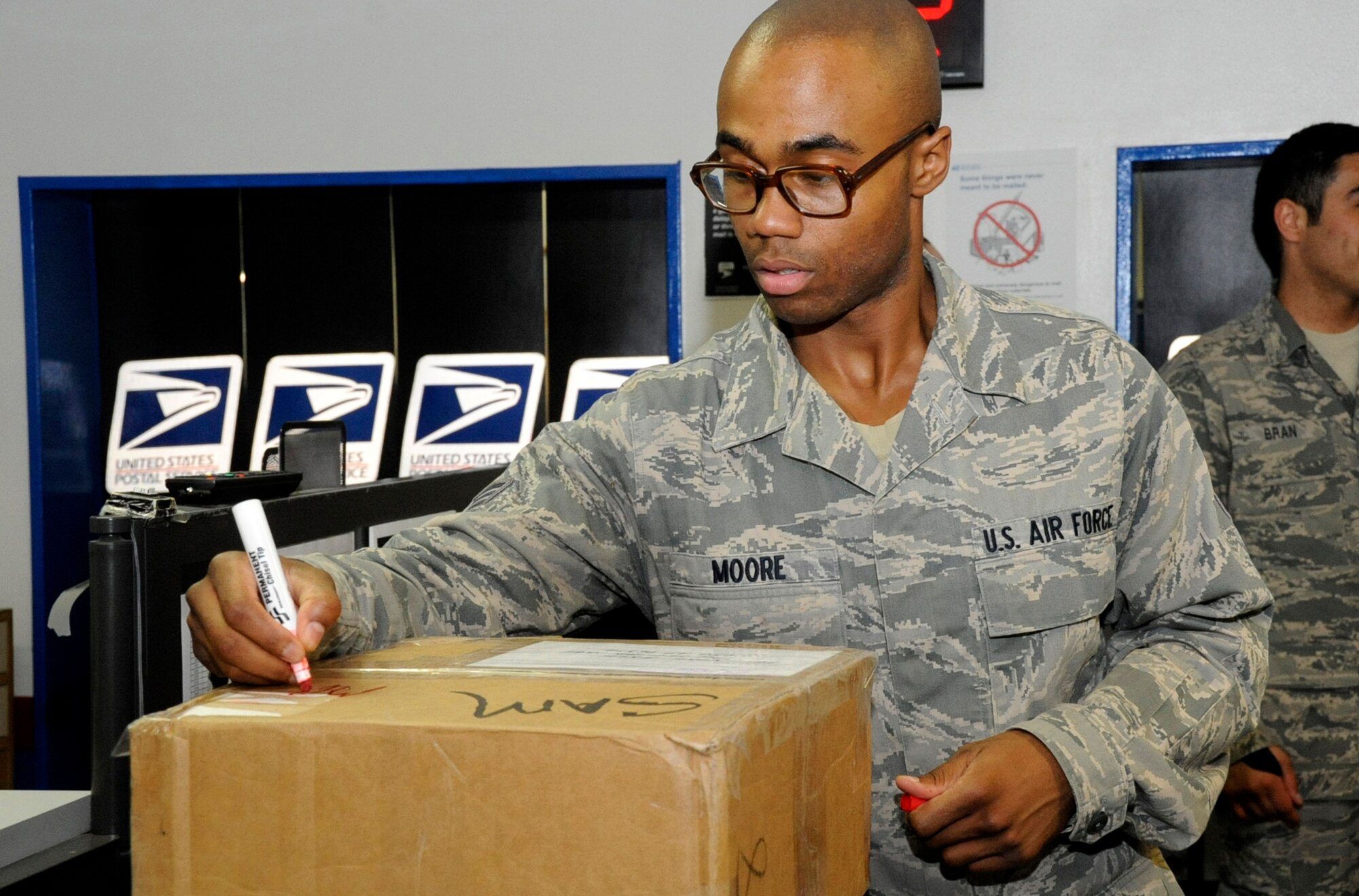 U.S. Air Force Senior Airman Brandon Moore, 35th Communications Squadron postal clerk, marks a package for delivery at Misawa Air Base, Japan, June 27, 2013. Each package is marked by weight and distance it needs to travel, making packages easier to track. (U.S. Air Force photo by Airman 1st Class Kenna Jackson)