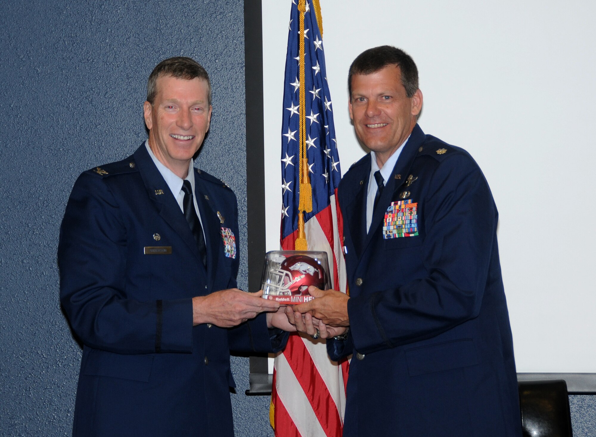 Col. Brian Burger, a lifelong LSU fan, right, proudly holds his Arkansas Razorback football helmet alongside, Col. Mark Anderson, 188th Fighter Wing commander. Burger, 188th Operations Group commander, was promoted to the rank of colonel during the ceremony held at the 188th. The helmet was a gift from Anderson. (U.S. Air National Guard photo by Senior Airman John Hillier/188th Fighter Wing Public Affairs)