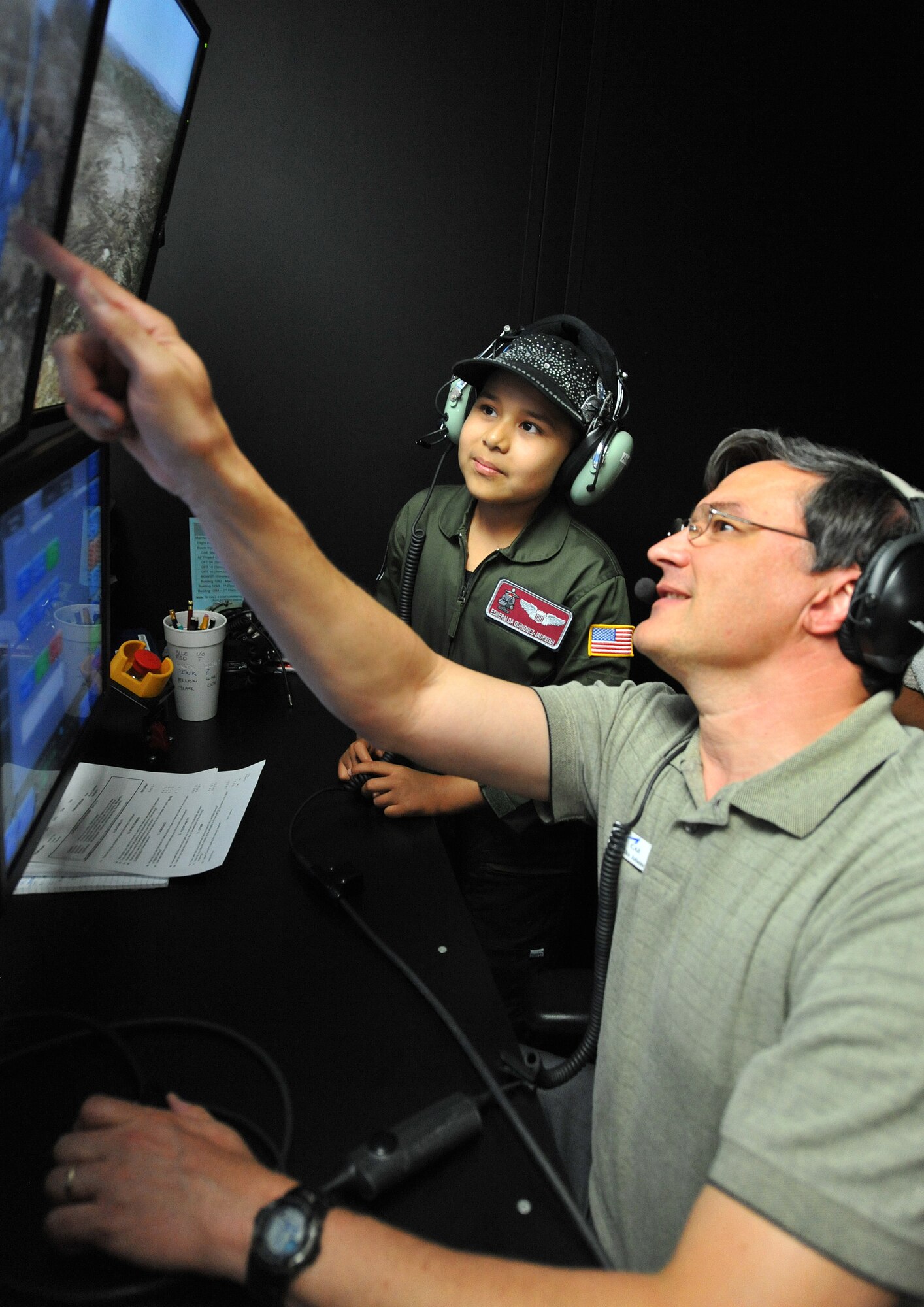 Michael Adams, CAE Boom Operator Instructor, shows Esmeralda Quinonez-Jauregui, 11-year-old Leukemia survivor, how to adjust weather conditions for a KC-135 Stratotanker Boom Operator Weapon System Trainer, June 27, 2013, at McConnell Air Force Base, Kan. Esmeralda was selected for the ‘Pilot for a Day’ program through a partnership with Wesley Medical Center, Wichita, Kan. and joined the McConnell community to see its daily operations and be an honorary member of the 384th Air Refueling Squadron. (U.S. Air Force photo/ Staff Sgt. Jess Lockoski)