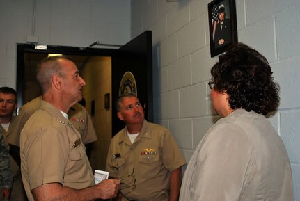 Rear Adm. William Roberts, left, commandant, Medical, Education and Training Campus; Capt. Adam Binford, center, commanding officer for the Navy Operational Support Center; and Suzanne Pedraza, lead case manager at the Wounded Ill & Injured Annex, stop at a photo of Seaman Apprentice Sidney O'Neill during a tour of the Annex spaces. O'Neill's photo is featured in the Annex as a tribute to her service. She passed away in March after battling cancer. The tour was part of a June 25 ribbon-cutting ceremony officially opening the Annex at the Navy Operational Support Center, Joint Base San Antonio-Fort Sam Houston. The Annex will serve as an administrative liaison for Navy, Marine Corps and Coast Guard members receiving treatment through the San Antonio Military Medical Center at JBSA-FSH. Annex staff will also provide support to service members' families and a better means of communication, patient advocacy and navigation through complex medical issues while service members receive treatment. The Annex is a detachment of the Naval Health Clinic Corpus Christi.
